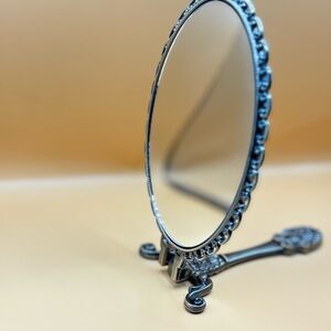 Silver Circular Mirror with Intricate Frame and Curved Stand